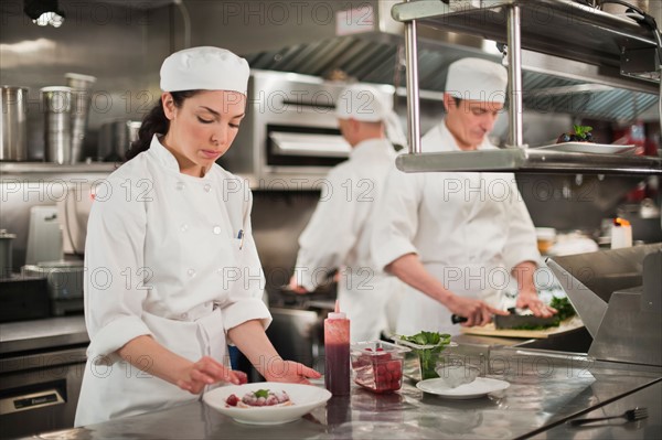 Chefs preparing food in kitchen.