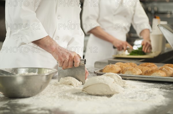 Chef cutting pastry to make rolls.