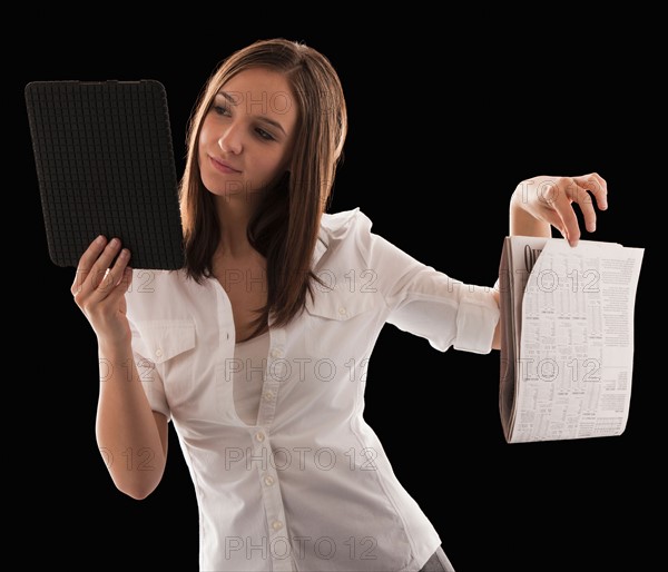 Young attractive businesswoman comparing financial results with financial column in newspaper. Photo : Mike Kemp