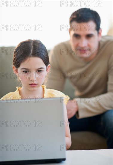 Daughter (8-9) and father using laptop .