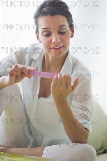 Attractive young woman filing nails.
