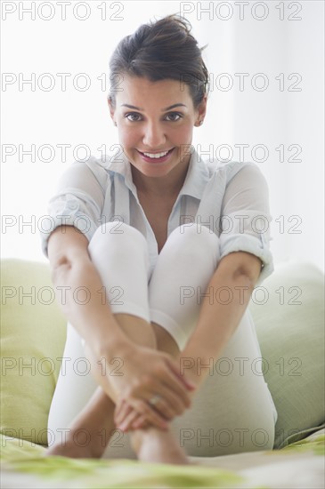 Portrait of cheerful young woman sitting with legs crossed.