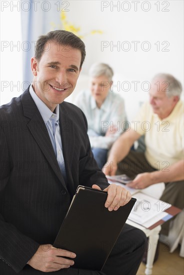 Portrait of businessman, senior couple in the background.