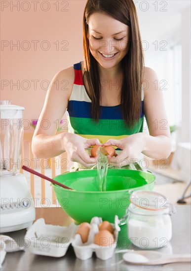 Young woman preparing food in kitchen. Photo : Jamie Grill Photography