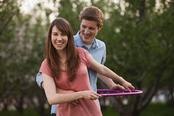 Young couple using plastic hoop in orchard. Photo : Mike Kemp