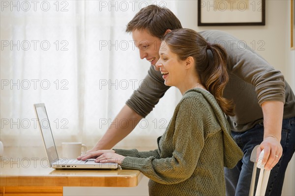 Couple using laptop at home. Photo : Rob Lewine