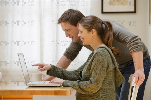 Couple using laptop at home. Photo : Rob Lewine