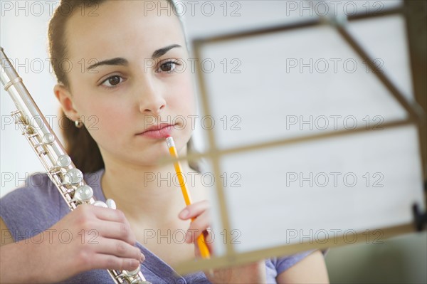 Girl with flute reading sheet music.
