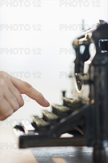 Close-up of man's hand typing on antique typewriter.