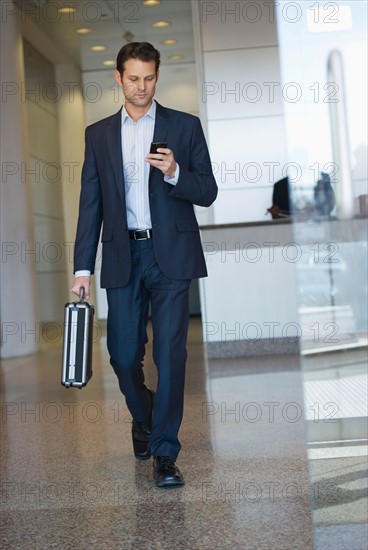 Businessman leaving office and using PDA.