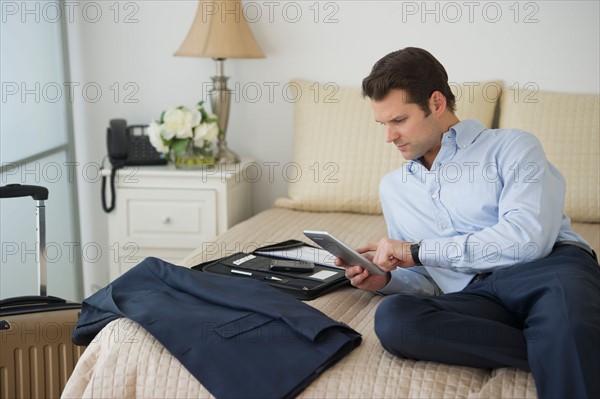 Businessman using digital tablet in hotel room.