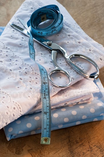 Close-up of folded textiles with scissors and tape measure.