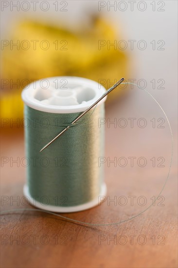 Close-up of green thread spool with needle.