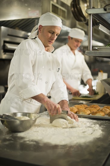 Chef cutting pastry to make rolls.