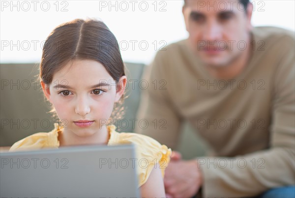 Daughter (8-9) and father using laptop .