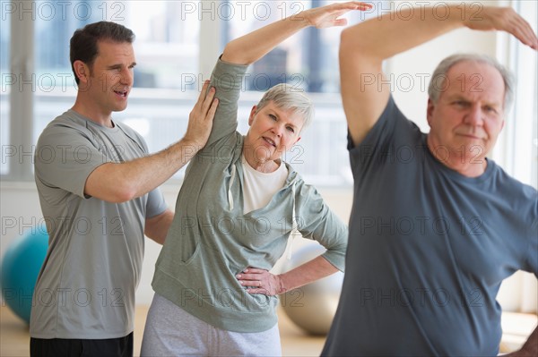 Man assisting senior people exercising.