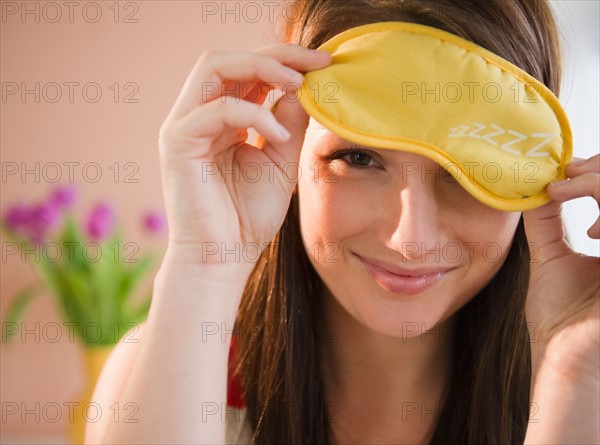 Young woman holding yellow sleep mask. Photo : Jamie Grill Photography