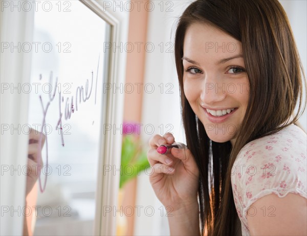Young woman writing on mirror with lipstick. Photo : Jamie Grill Photography