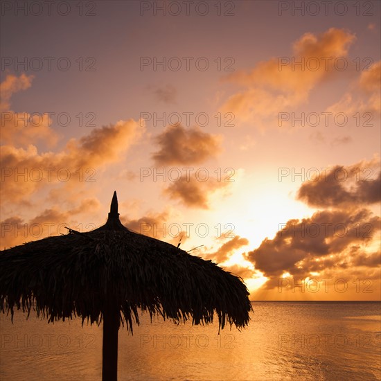 Aruba, silhouette of palapa on beach at sunset. Photo : Daniel Grill