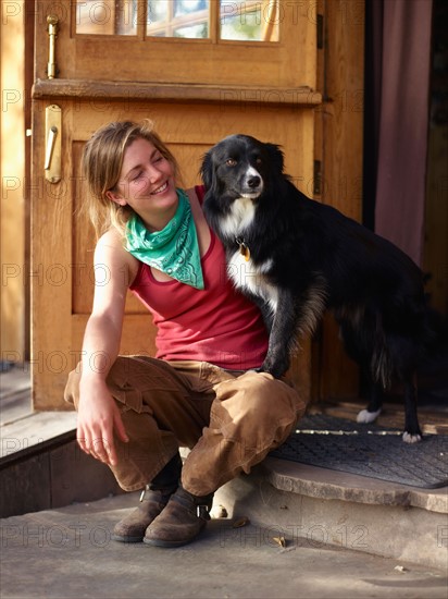 Young woman with dog sitting on porch. Photo : John Kelly