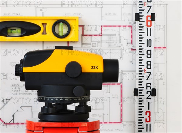 Close-up of theodolite, blueprint in the background.