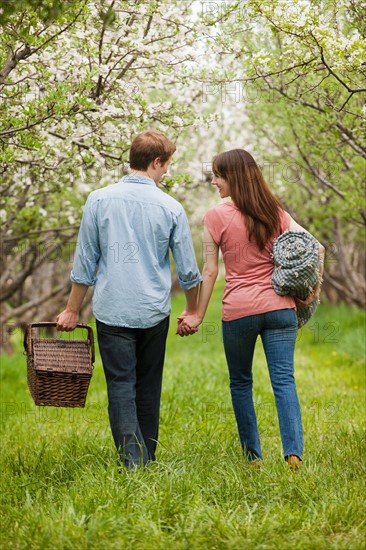 USA, Utah, Provo, Young couple with picnic basket in orchard. Photo : Mike Kemp