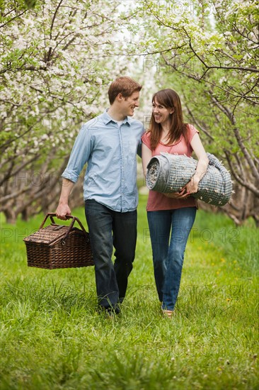 USA, Utah, Provo, Young couple with picnic basket in orchard. Photo : Mike Kemp