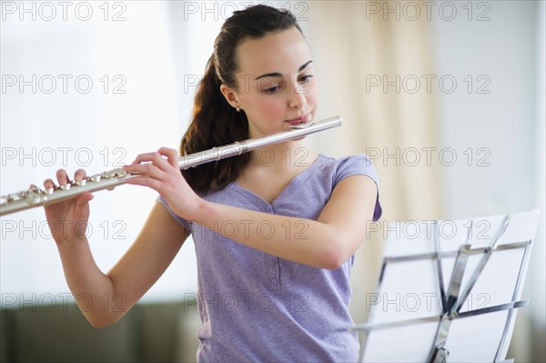 Teenage girl (14-15) playing flute .