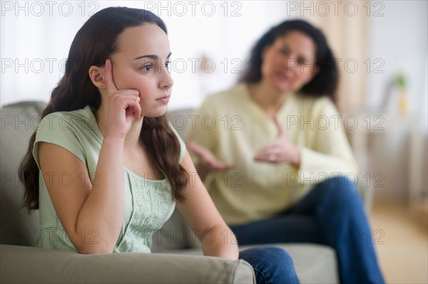 Mother with teenage girl (14-15) sitting on sofa.