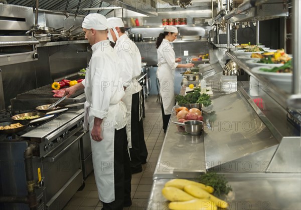 Chefs preparing food in kitchen.