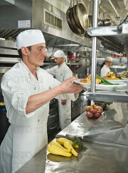 Chefs preparing food in kitchen.