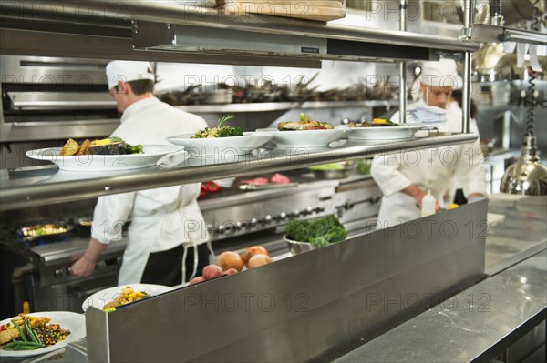 Chefs preparing food in kitchen.