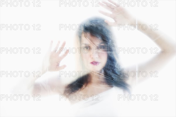 Young attractive woman looking from behind white sheet.