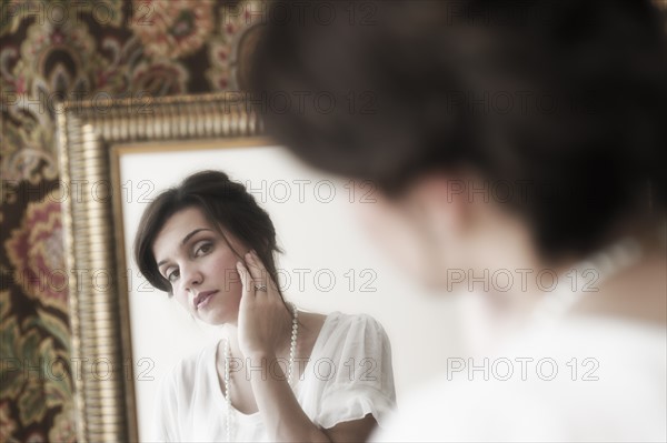 Old-fashioned young woman looking at mirror reflection.