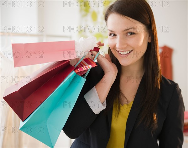 Young woman holding shopping bags. Photo : Jamie Grill Photography