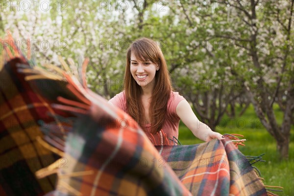 Young woman holding blanket in orchard. Photo : Mike Kemp