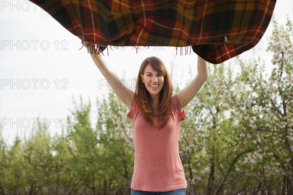 Young woman holding blanket in orchard. Photo : Mike Kemp