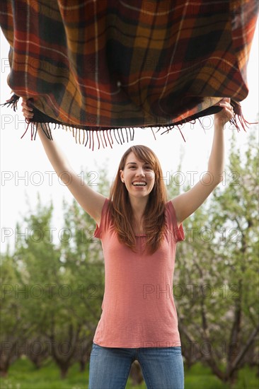 Young woman holding blanket in orchard. Photo : Mike Kemp