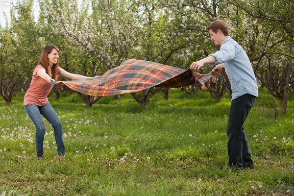 USA, Utah, Provo, Young couple holding blanket in orchard. Photo : Mike Kemp