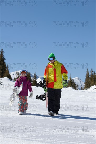 USA, Colorado, Telluride, Father and daughter (10-11) walking with snowboards in winter scenery. Photo : db2stock