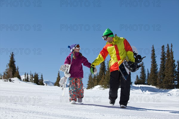 USA, Colorado, Telluride, Father and daughter (10-11) walking with snowboards in winter scenery. Photo : db2stock