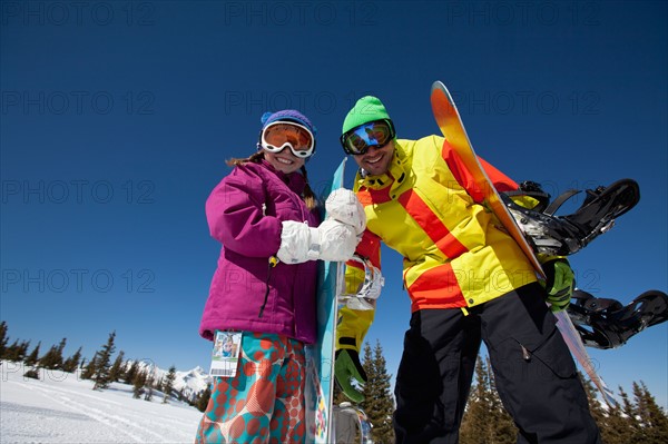 USA, Colorado, Telluride, Father and daughter (10-11) posing with snowboards in winter scenery. Photo : db2stock