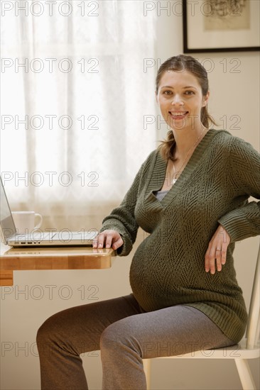 Portrait of expecting mother with laptop. Photo : Rob Lewine