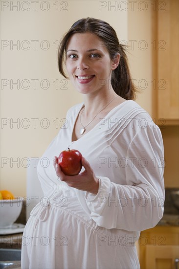 Portrait of expecting mother holding apple. Photo : Rob Lewine