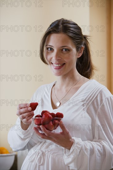 Portrait of expecting mother eating strawberries. Photo : Rob Lewine