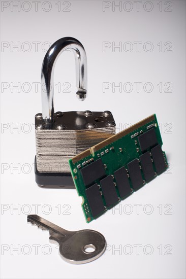 Close-up studio shot of silver padlock with key and computer chip. Photo : Winslow Productions