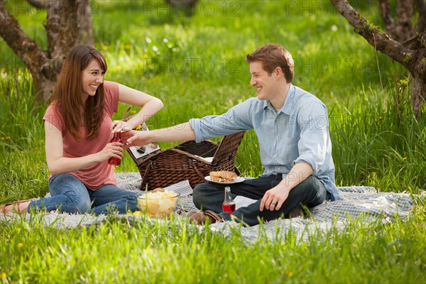 USA, Utah, Provo, Young couple having picnic in orchard. Photo : Mike Kemp