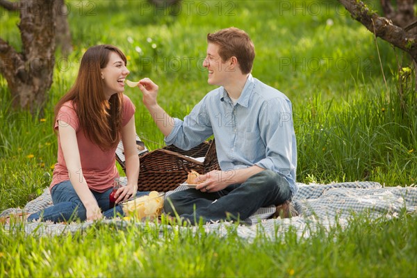 USA, Utah, Provo, Young couple having picnic in orchard. Photo : Mike Kemp