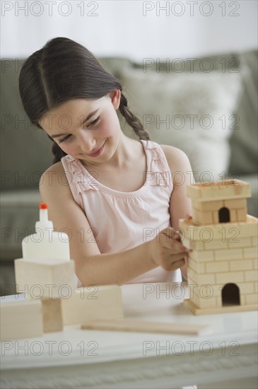 Girl (8-9) building toy castle.