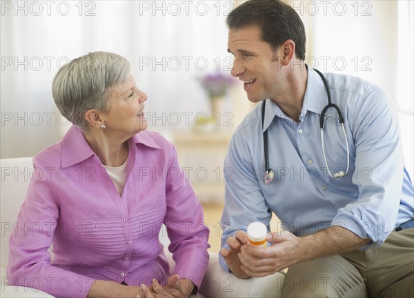 Smiling doctor giving medicine bottle to senior woman.